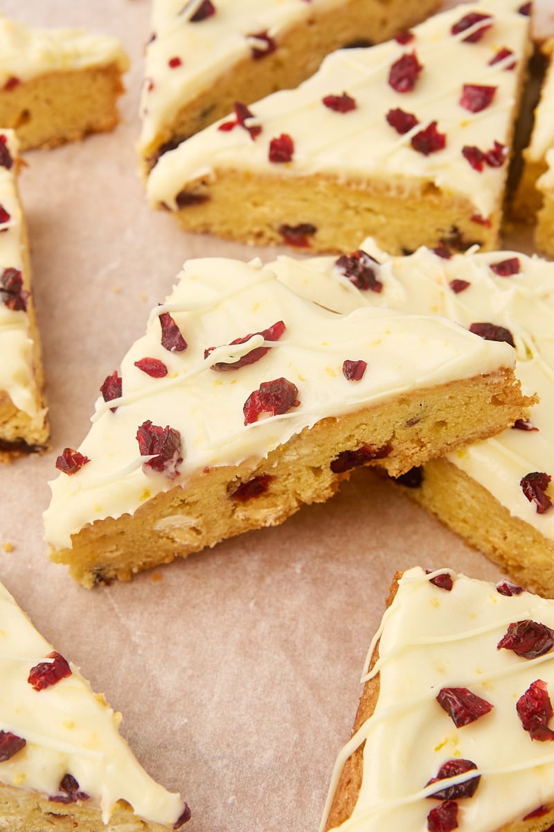 several cranberry bliss bars on a parchment-covered cutting board