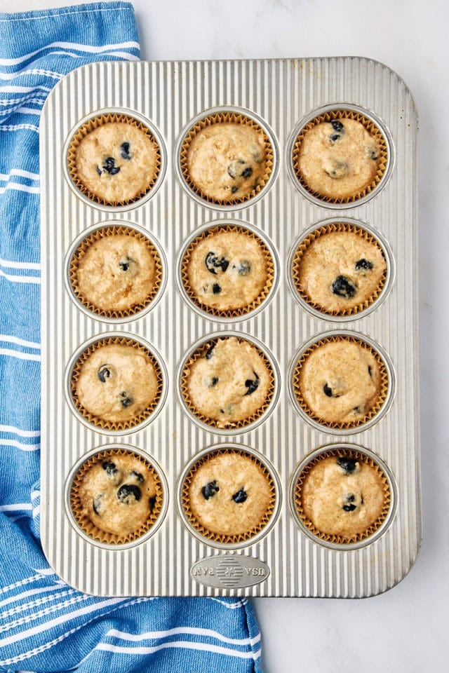 overhead view of whole wheat blueberry muffin batter in a lined muffin pan