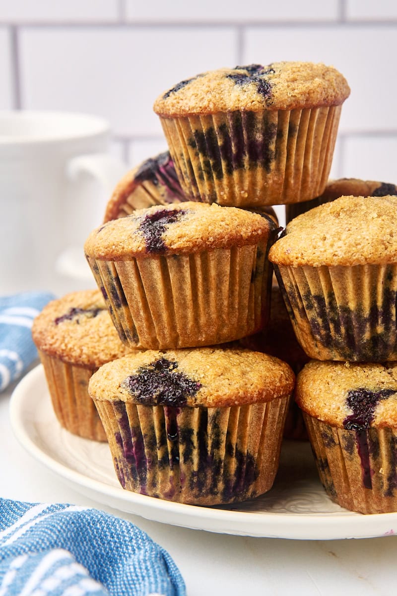 whole wheat blueberry muffins piled on a white plate for serving