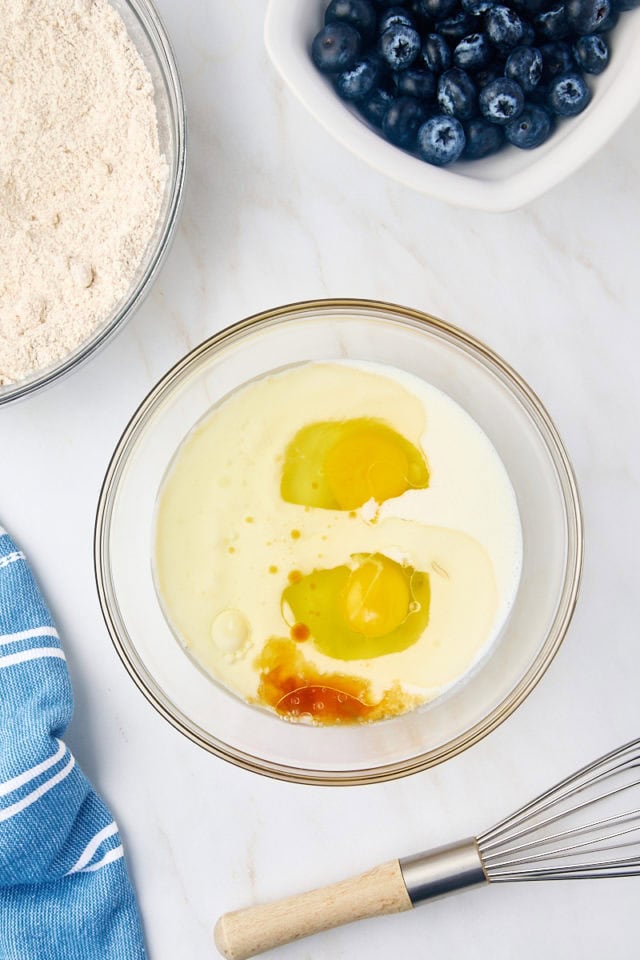 overhead view of vegetable oil, buttermilk, eggs, and vanilla extract in a glass mixing bowl