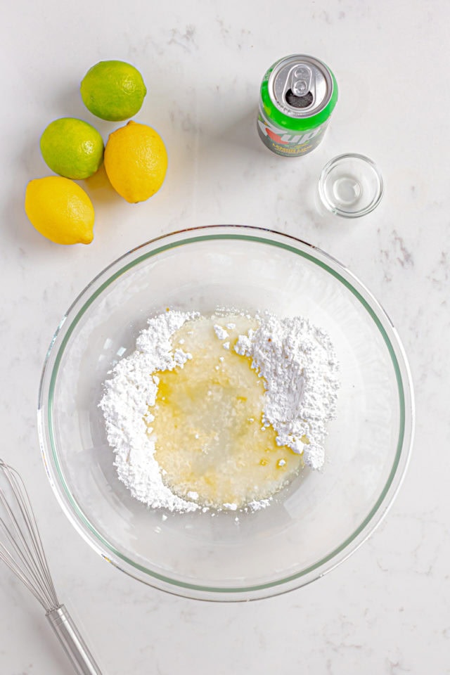 overhead view of confectioners' sugar, 7UP, lemon juice, and vanilla extract in a glass bowl