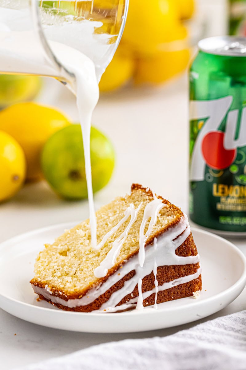 glaze drizzling over a slice of 7UP cake on a white plate