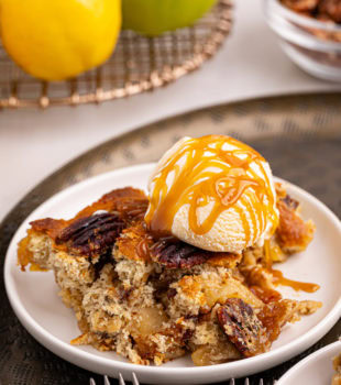 a serving of caramel apple pear cobbler topped with vanilla ice cream and caramel sauce
