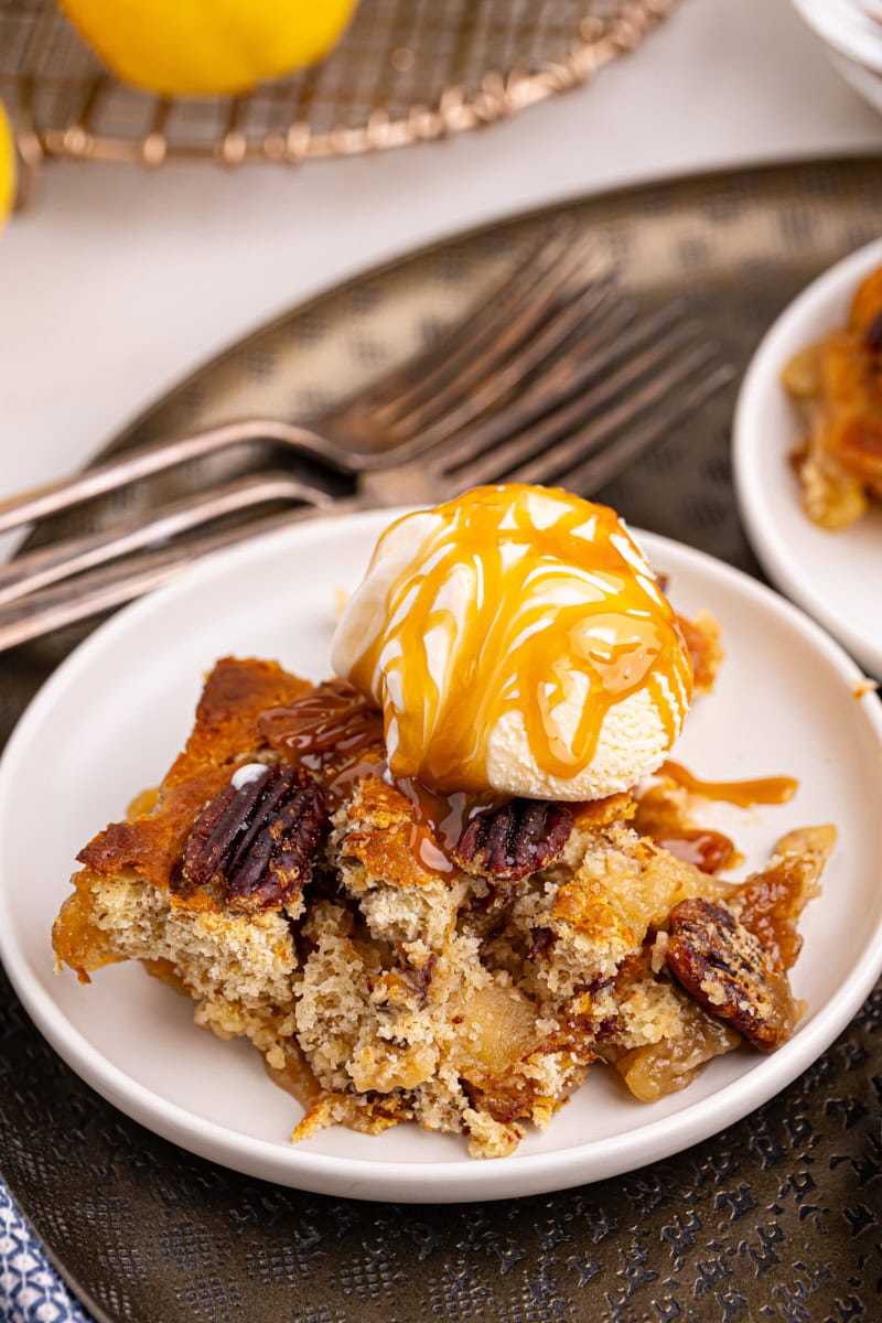 a serving of caramel apple pear cobbler topped with ice cream and caramel sauce