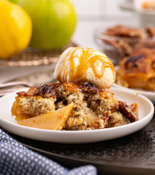 a serving of caramel apple pear cobbler topped with ice cream and caramel sauce