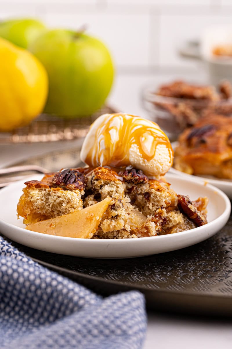 a serving of caramel apple pear cobbler topped with ice cream and caramel sauce