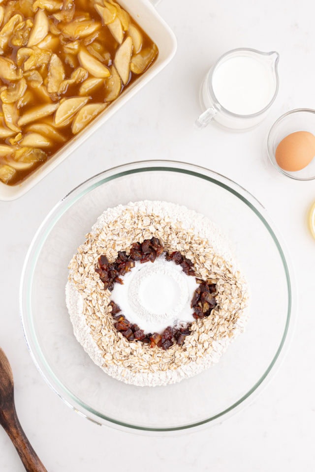 overhead view of flour, oats, dates, baking powder, and salt in a glass mixing bowl