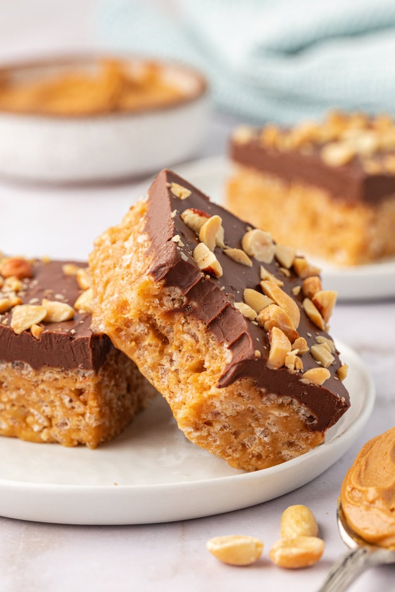 a chocolate peanut butter rice crispy treat with a bite missing, on a plate with another rice crispy treat