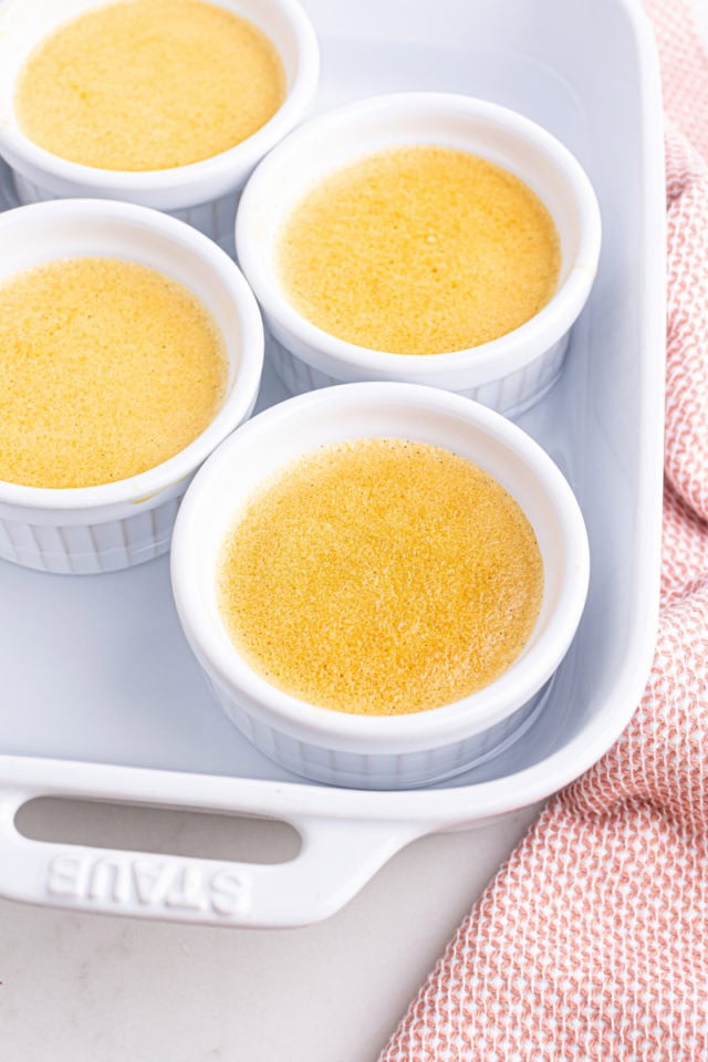 four ramekins of freshly baked crème brûlée in a baking pan