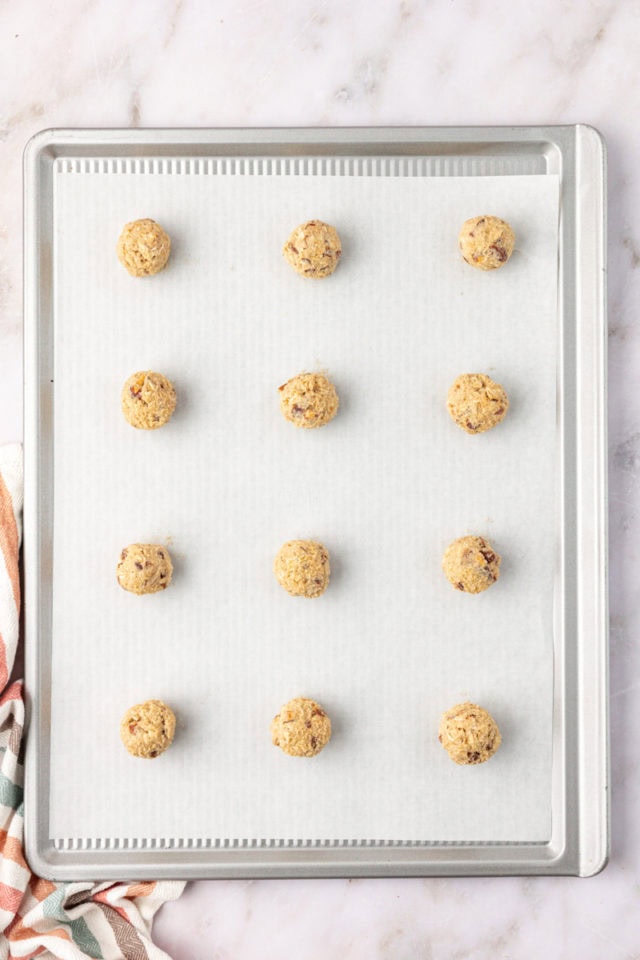 overhead view of oatmeal date cookie dough portioned on a lined baking sheet