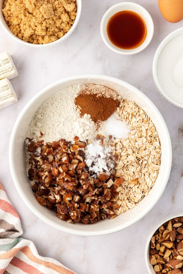 overhead view of dry ingredients for oatmeal date cookies in a white bowl