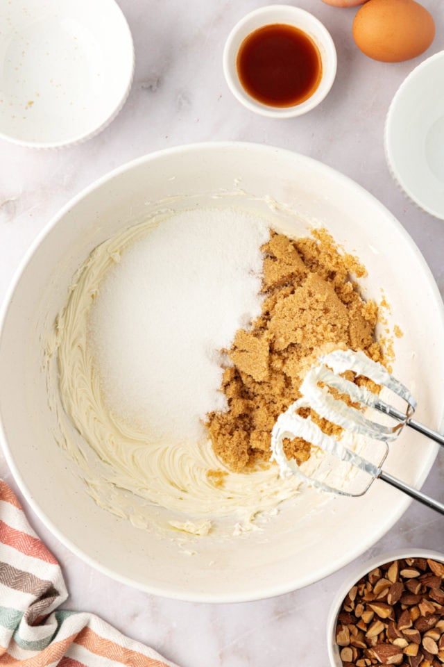 overhead view of granulated sugar and brown sugar added to creamed butter in a mixing bowl