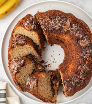 partially sliced banana coffee cake on a white cake plate