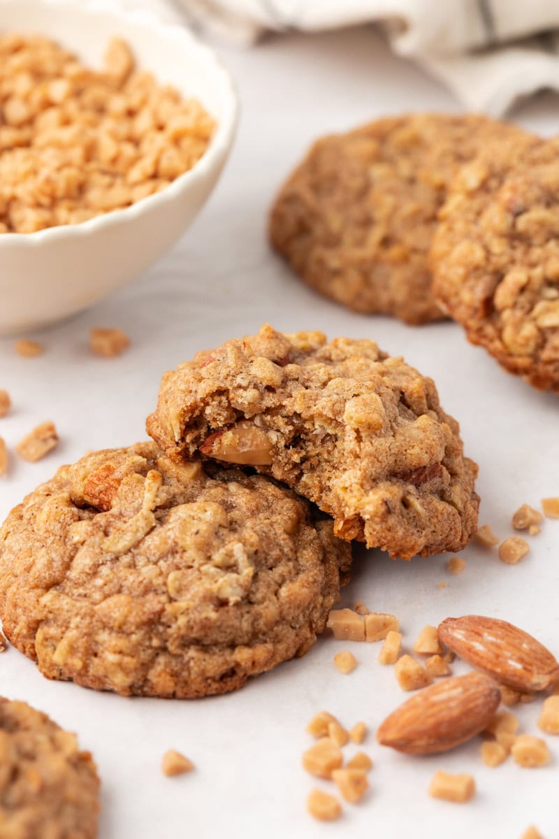 two toffee almond oatmeal cookies with a bite missing from one of them