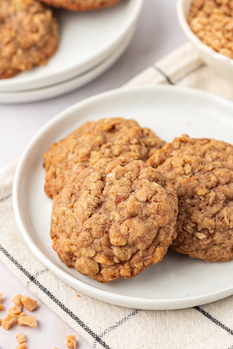 three toffee almond oatmeal cookies on a white plate