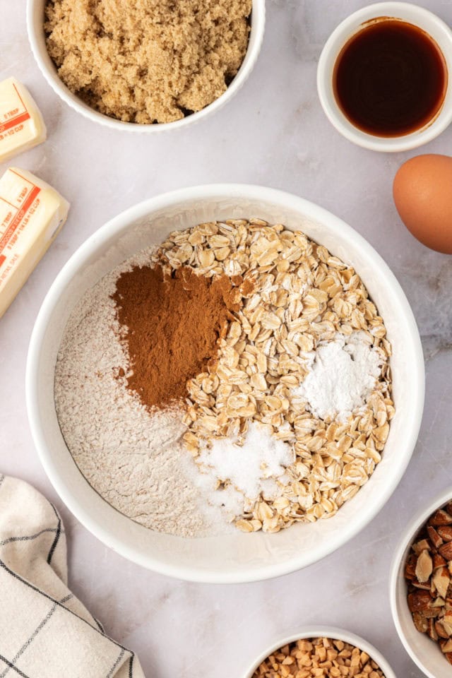 overhead view of whole wheat flour, oats, baking powder, salt, and cinnamon in a mixing bowl