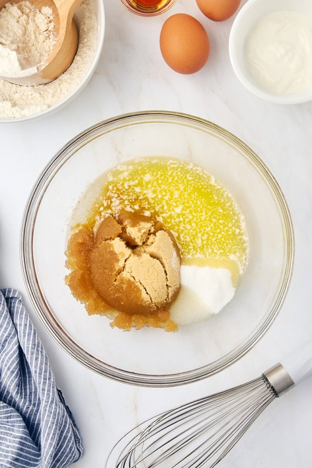 overhead view of melted butter, oil, brown sugar, and sugar in a glass mixing bowl