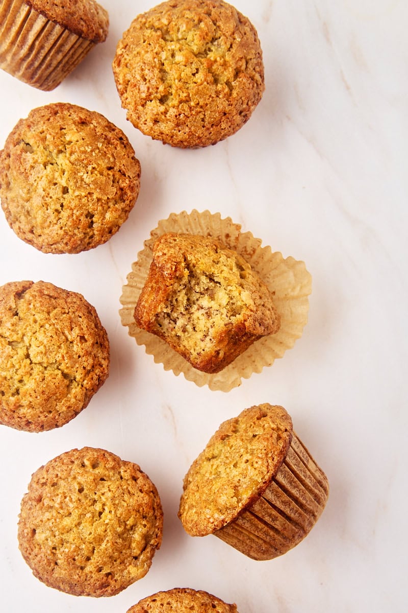 overhead view of several banana muffins, with a bite missing from one of them