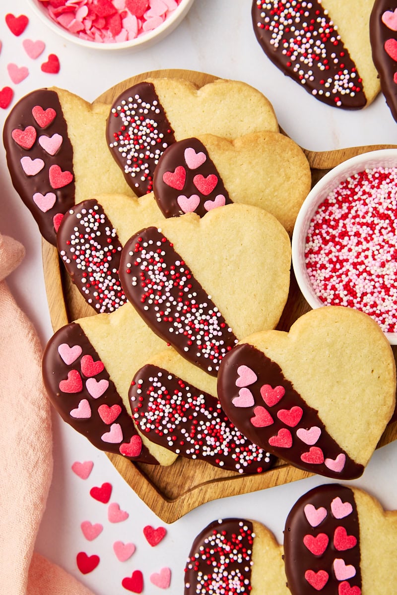 overhead view of heart-shaped chocolate-dipped shortbread cookies on a heart-shaped wooden tray