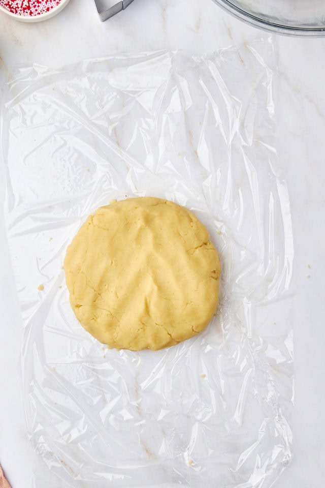 overhead view of a disc of shortbread dough on a sheet of plastic wrap