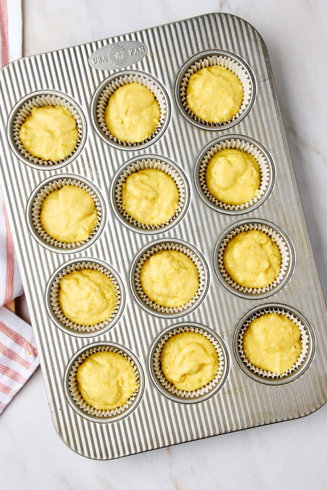 overhead view of orange ricotta muffin batter portioned into a muffin pan