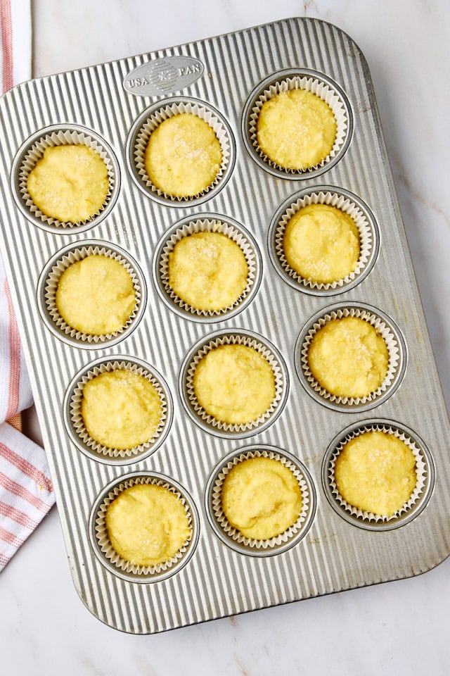 overhead view of orange ricotta muffins topped with coarse sugar and ready to go into the oven