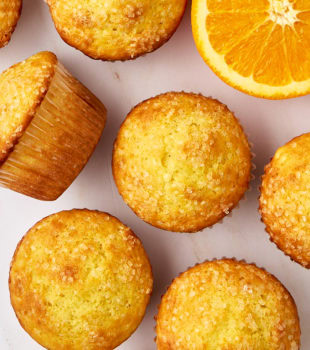 orange ricotta muffins scattered on a white countertop