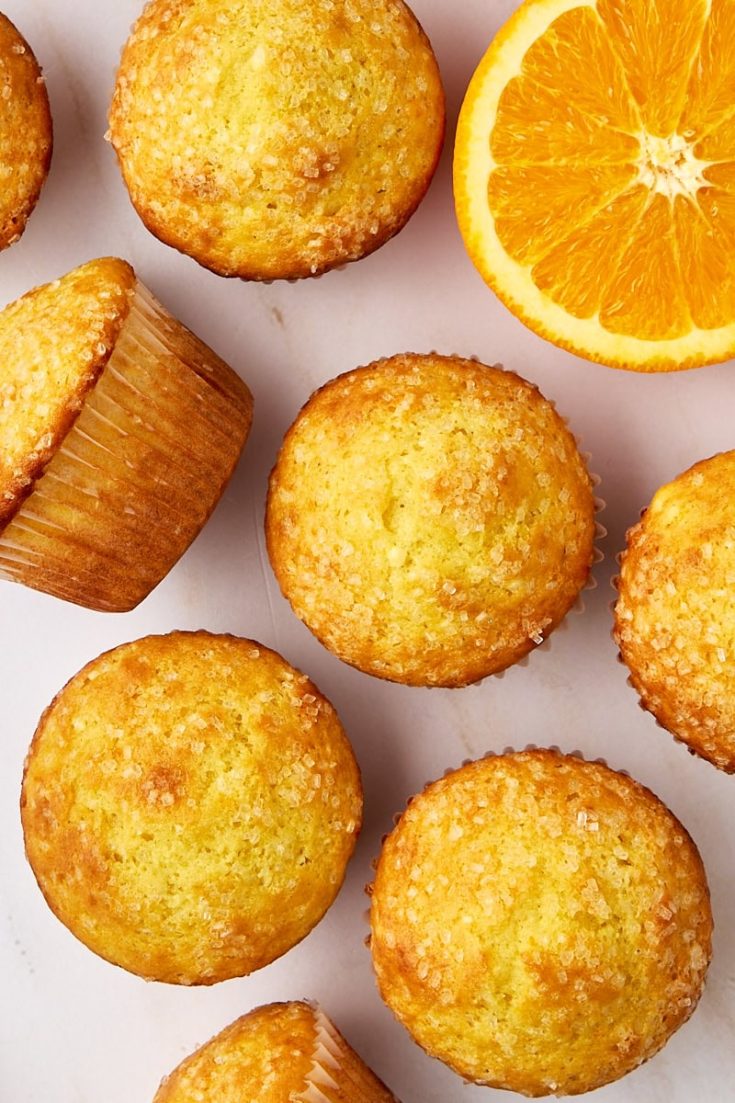 orange ricotta muffins scattered on a white countertop