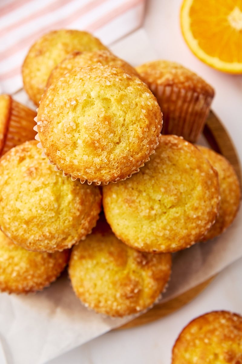 orange ricotta muffins stacked on a parchment-covered wooden plate