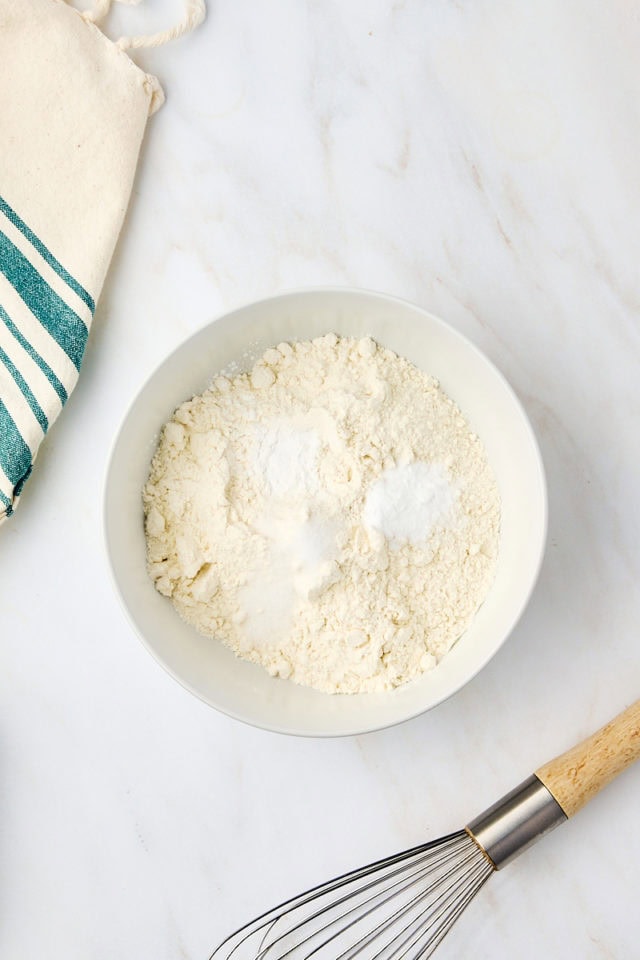 overhead view of flour, baking powder, baking soda, and salt in a white bowl