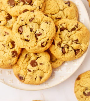 tahini chocolate chip cookies on a white plate surrounded by more cookies