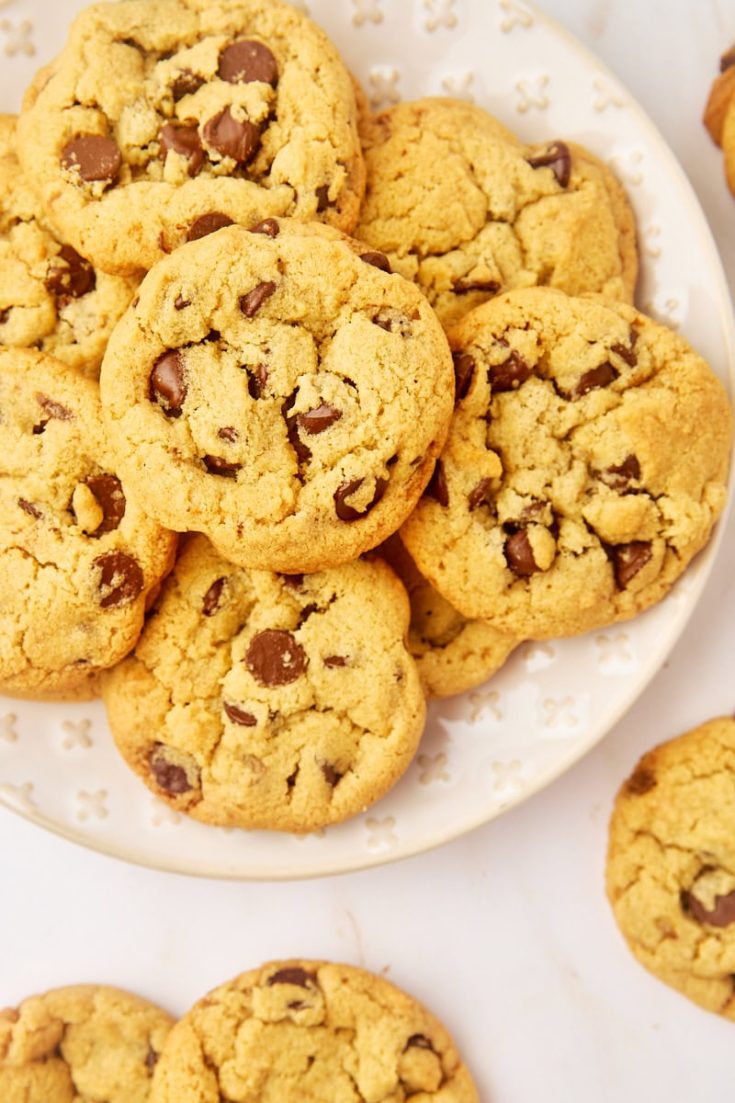 tahini chocolate chip cookies on a white plate surrounded by more cookies