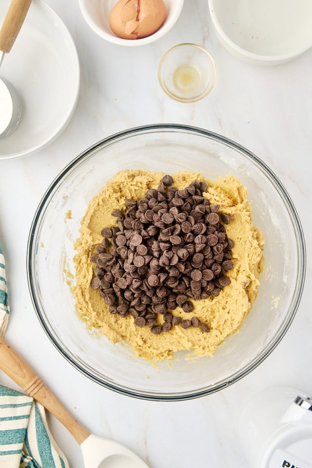 overhead view of chocolate chips added to cookie dough