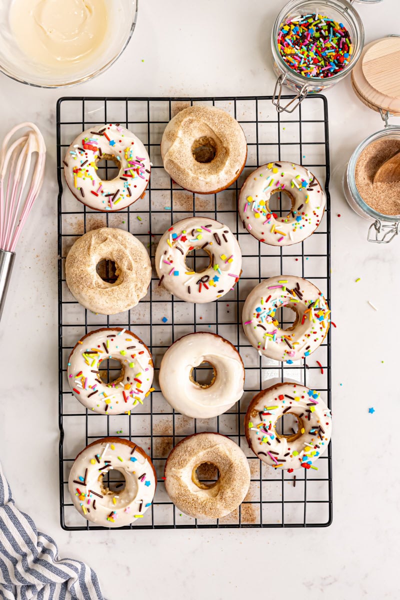 overhead view of baked doughnuts topped with glaze and various toppings like sprinkles and cinnamon-sugar