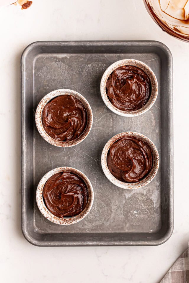 overhead view of chocolate lava cake batter divided into four ramekins on a baking sheet