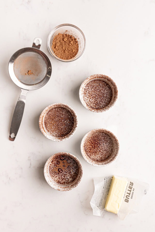 overhead view of four ramekins buttered and dusted with cocoa powder