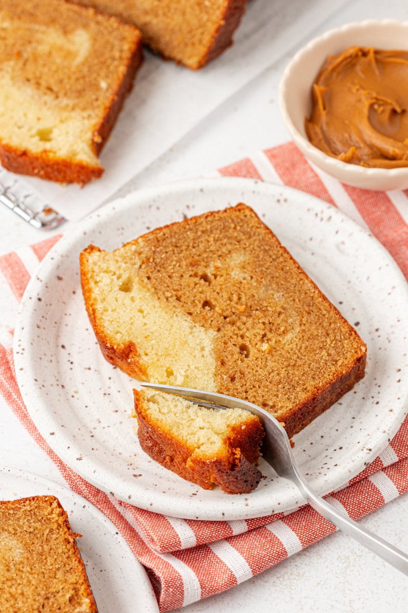 a slice of marbled cookie butter cake on a plate with a bite of cake on a fork