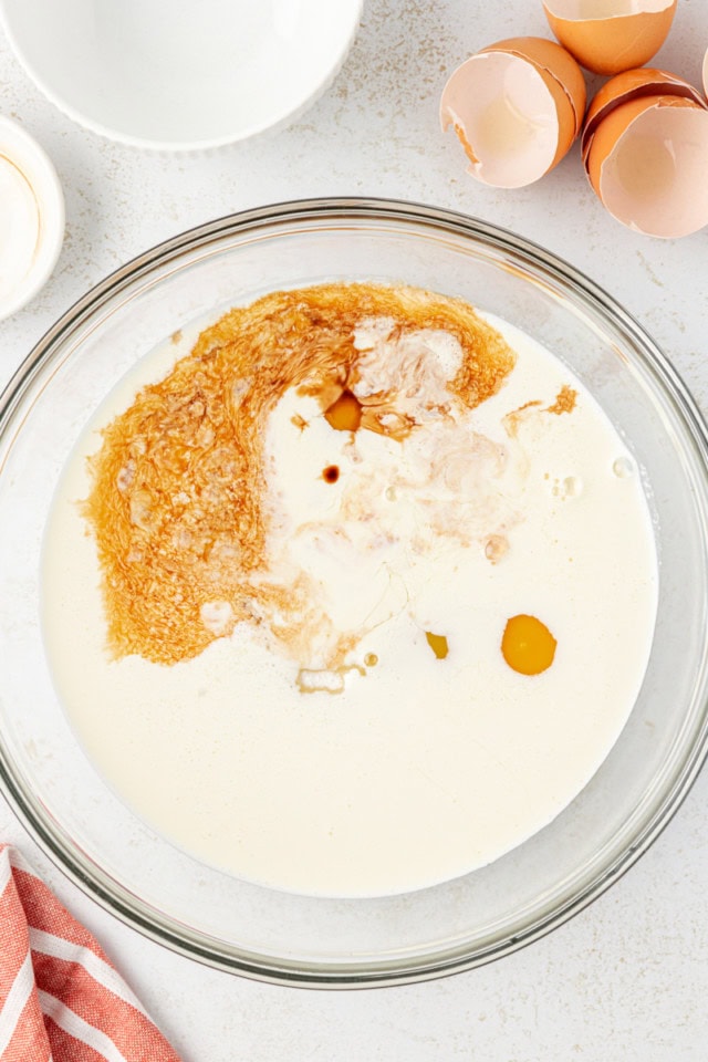 overhead view of heavy cream, eggs, sugar, and vanilla extract in a mixing bowl