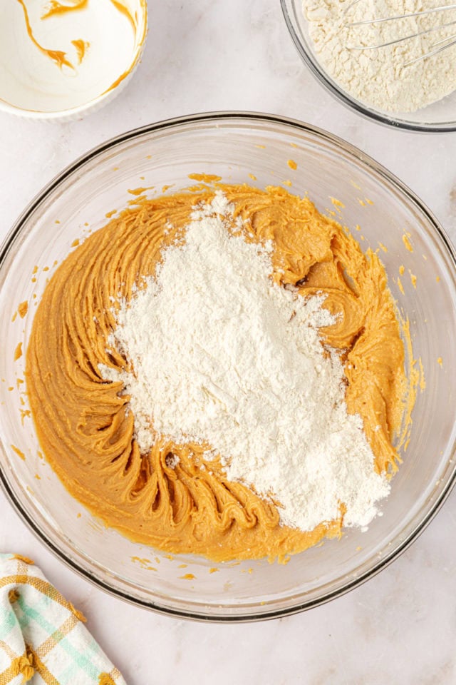 overhead view of dry ingredients added to wet ingredients for peanut butter cookie dough