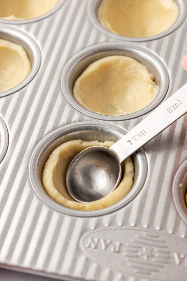 pie crust being shaped into a mini muffin pan