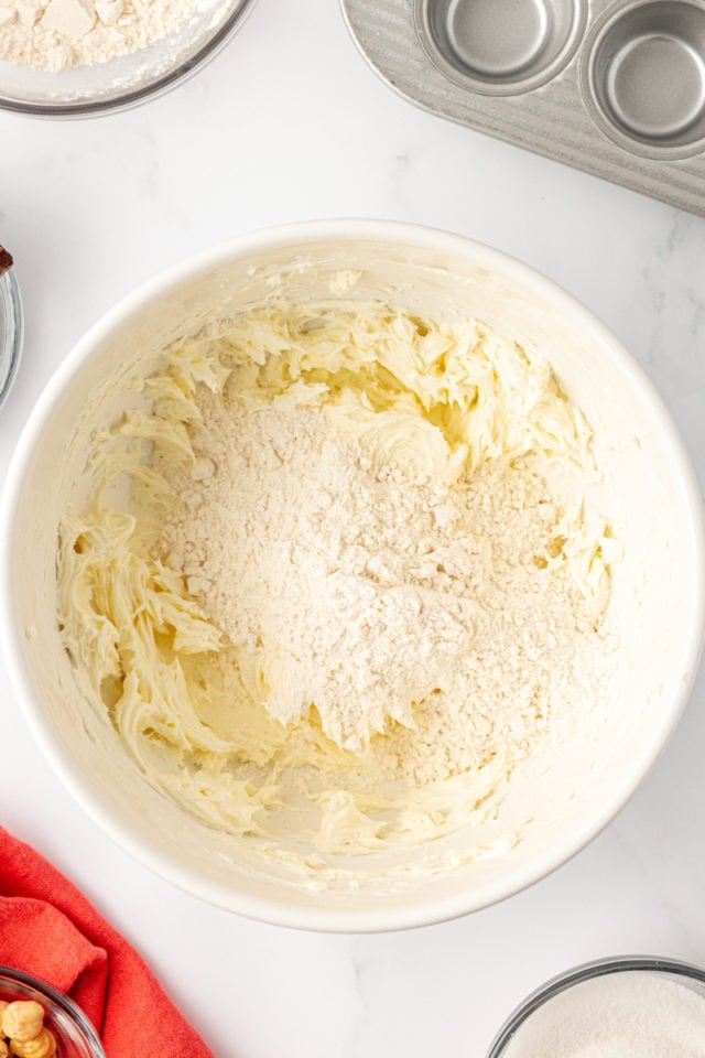 overhead view of flour added to creamed butter and cream cheese