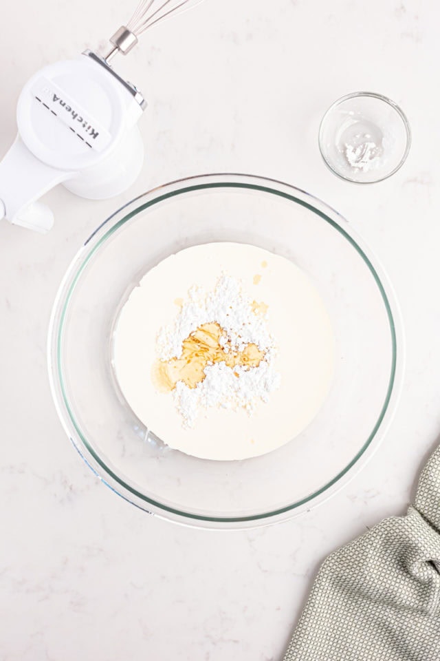 overhead view of heavy cream, confectioners' sugar, and vanilla in a mixing bowl