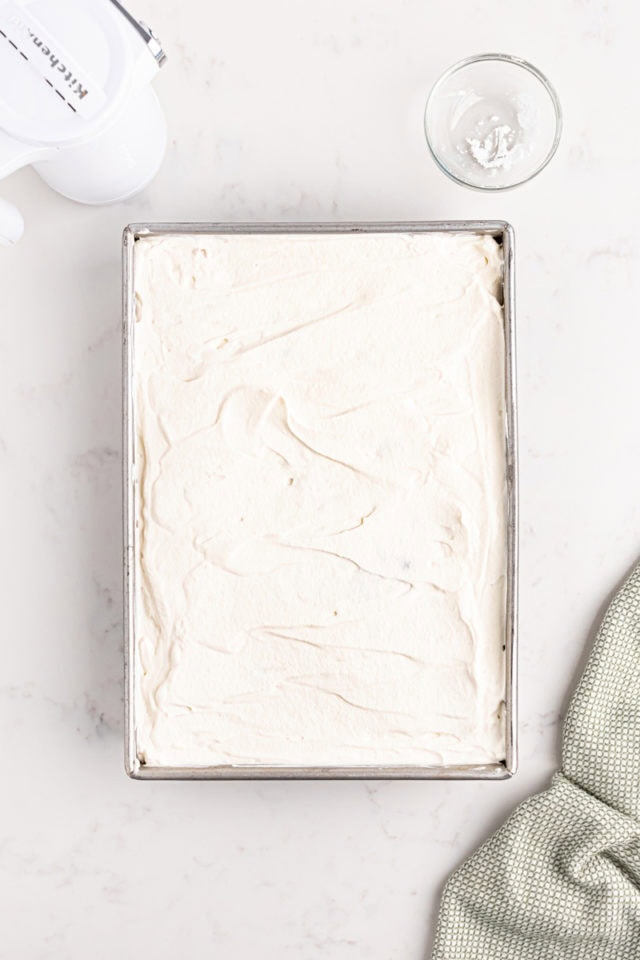 overhead view of whipped cream topping spread on top of tres leches cake