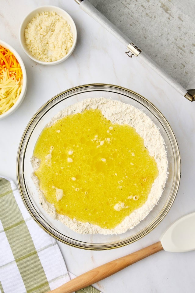 overhead view of wet ingredients added to dry ingredients for herb and cheese quick bread