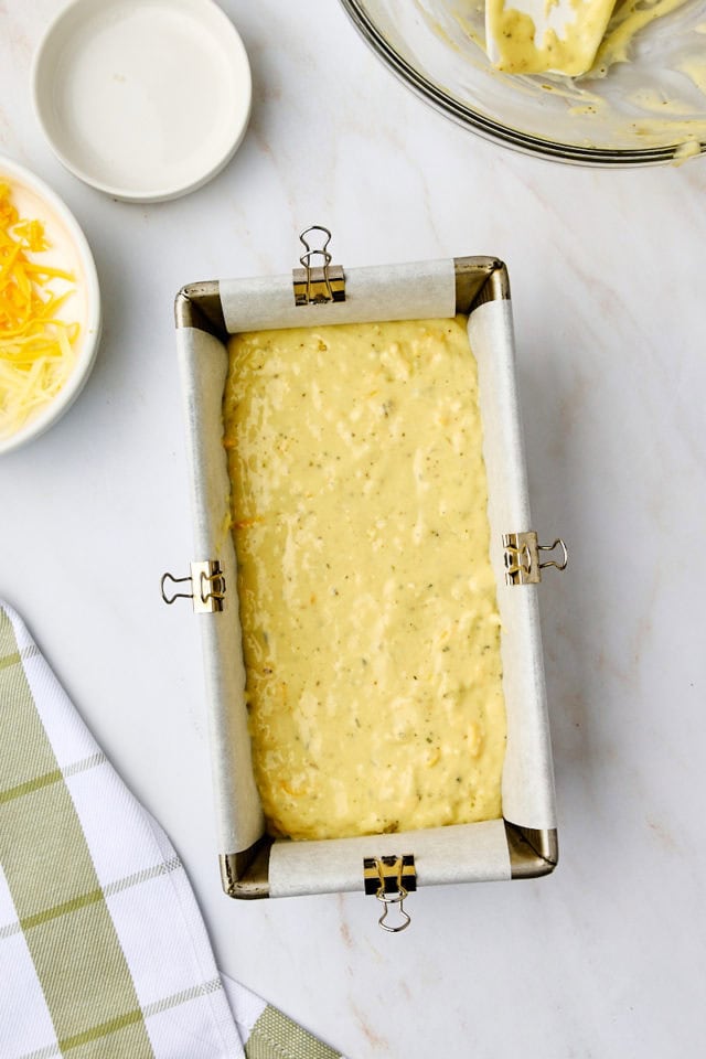 overhead view of herb and cheese quick bread batter in a loaf pan lined with parchment paper