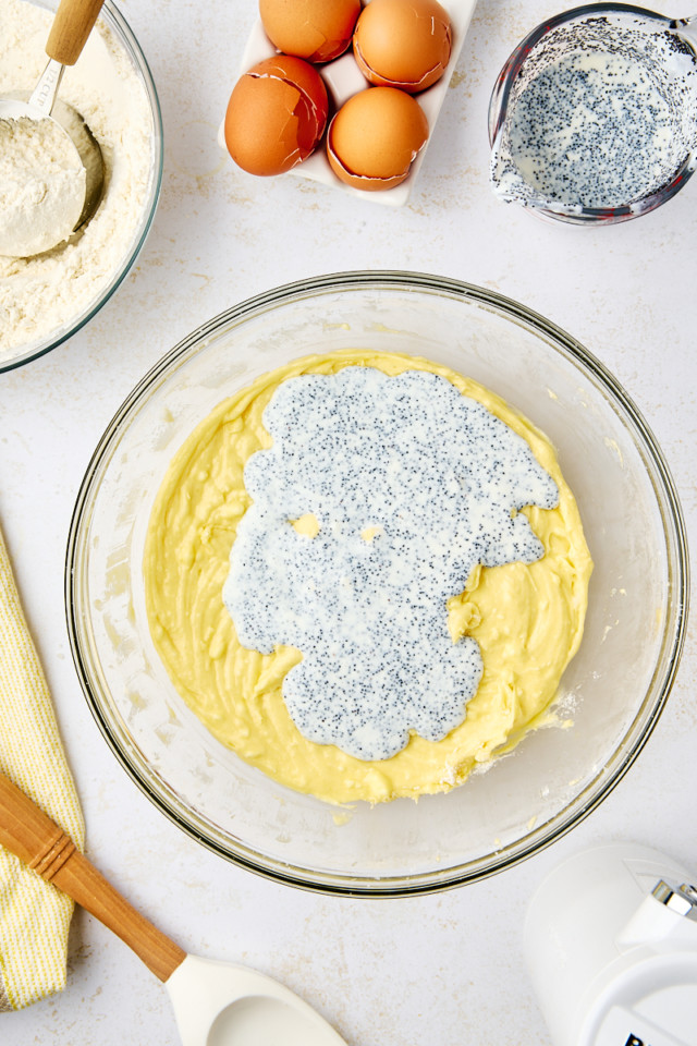 overhead view of buttermilk and poppy seeds added to lemon poppy seed cake batter