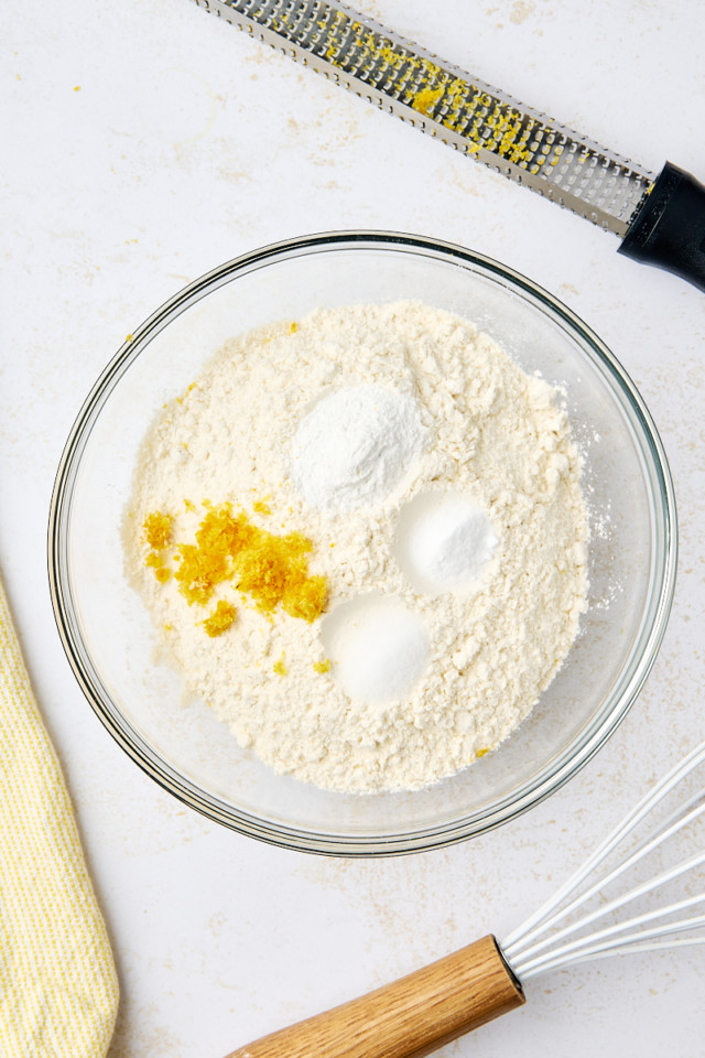 overhead view of flour, baking powder, baking soda, salt, and lemon zest in a mixing bowl