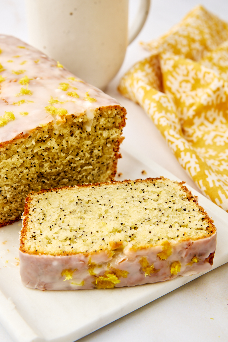 a slice of lemon poppy seed loaf next to remaining cake