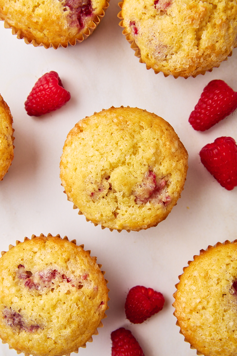 overhead view of lemon raspberry muffins and fresh raspberries on a white countertop