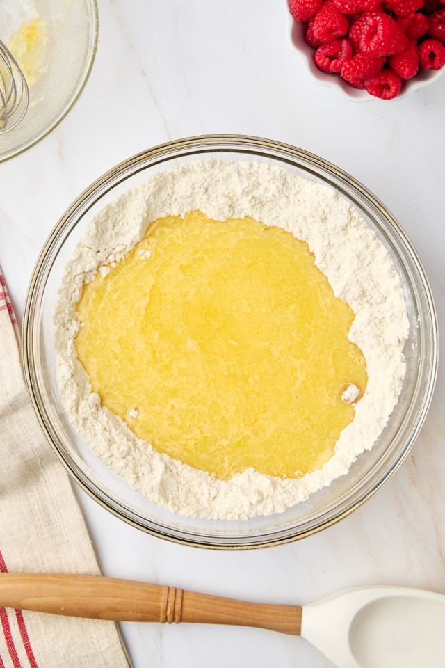 overhead view of wet ingredients added to dry ingredients for lemon raspberry muffins